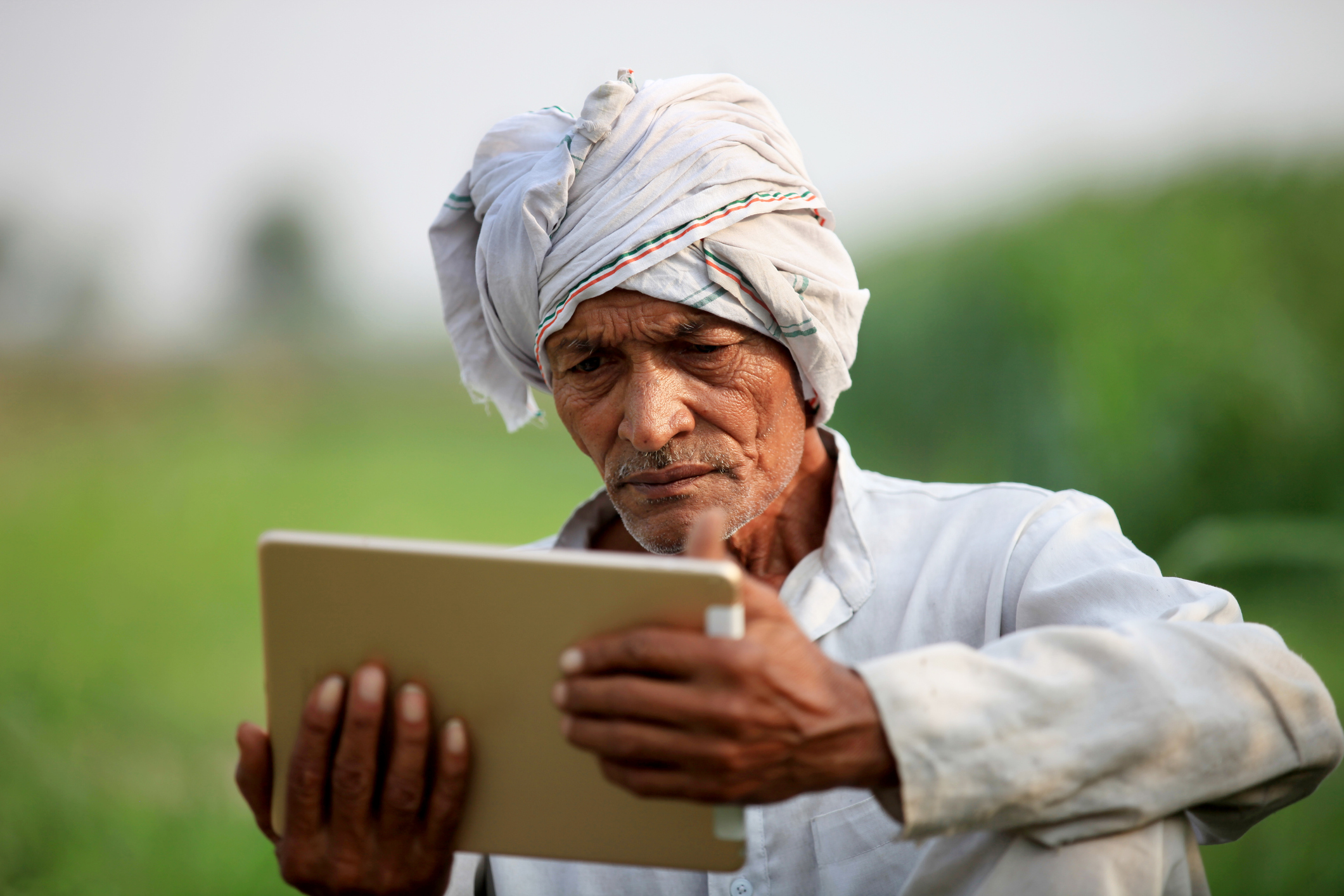 Old farmer holding digital tablet