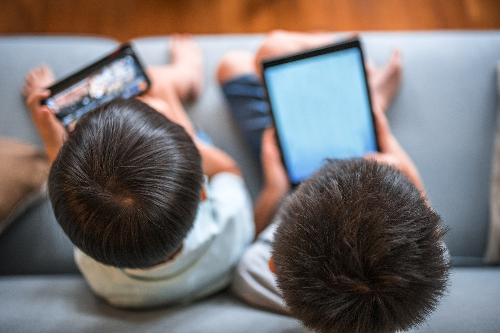 Boys using digital table and sitting on a sofa