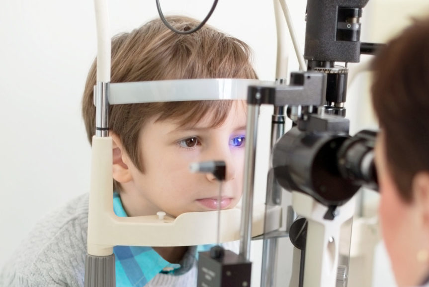 Optician monitoring young boy in eye clinic