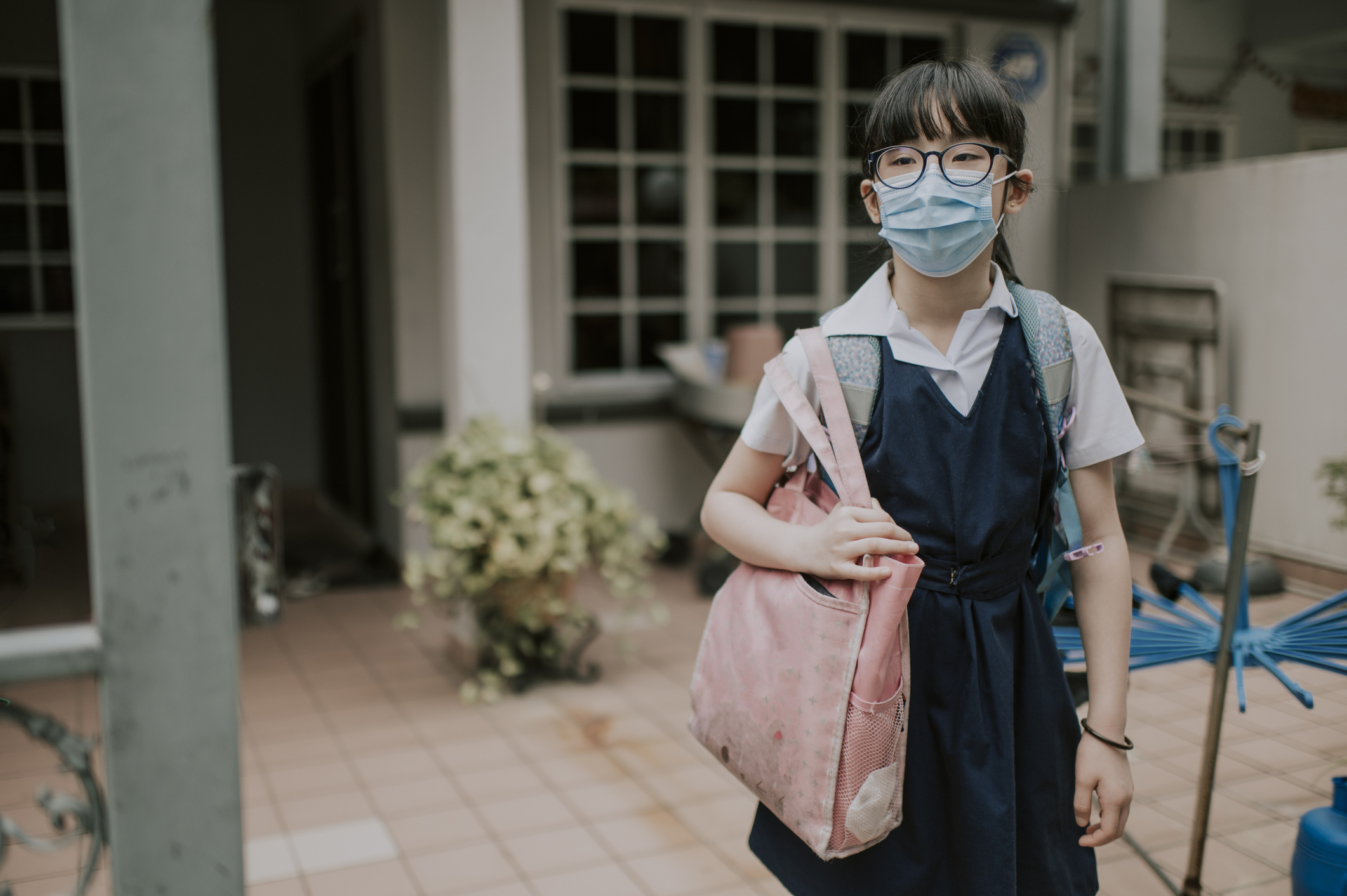 an asian chinese young girl going to school departing from home with facemask as new normal