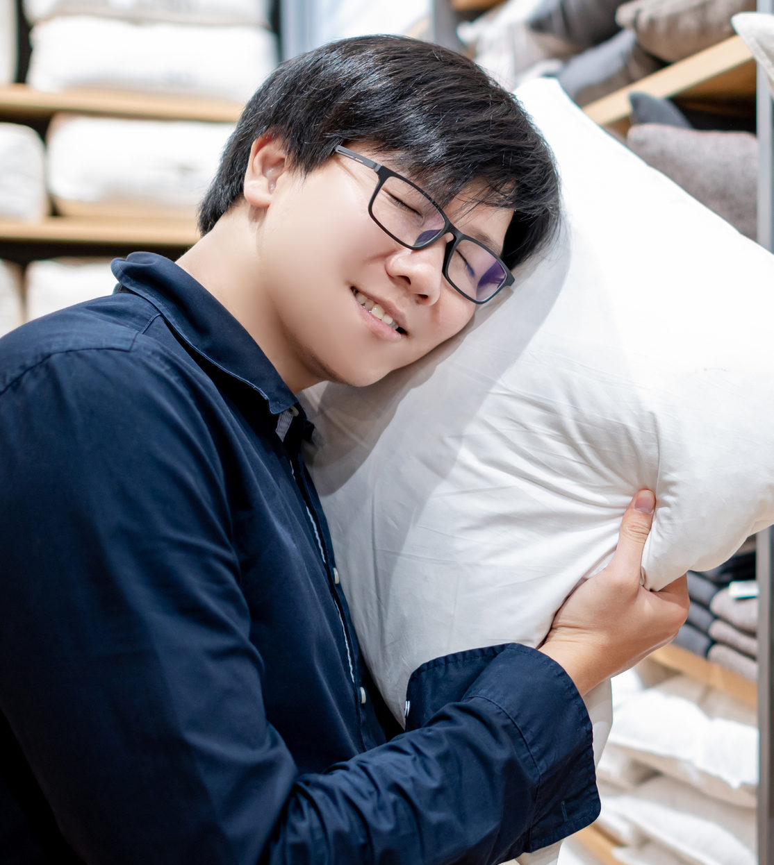 Asian man choosing pillow in furniture store