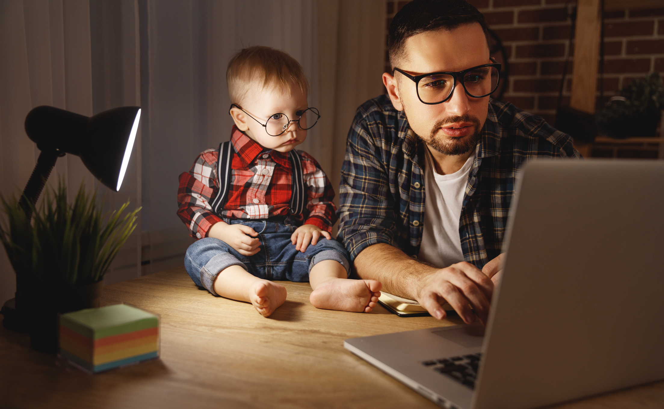 father and son baby work at home at computer in dark