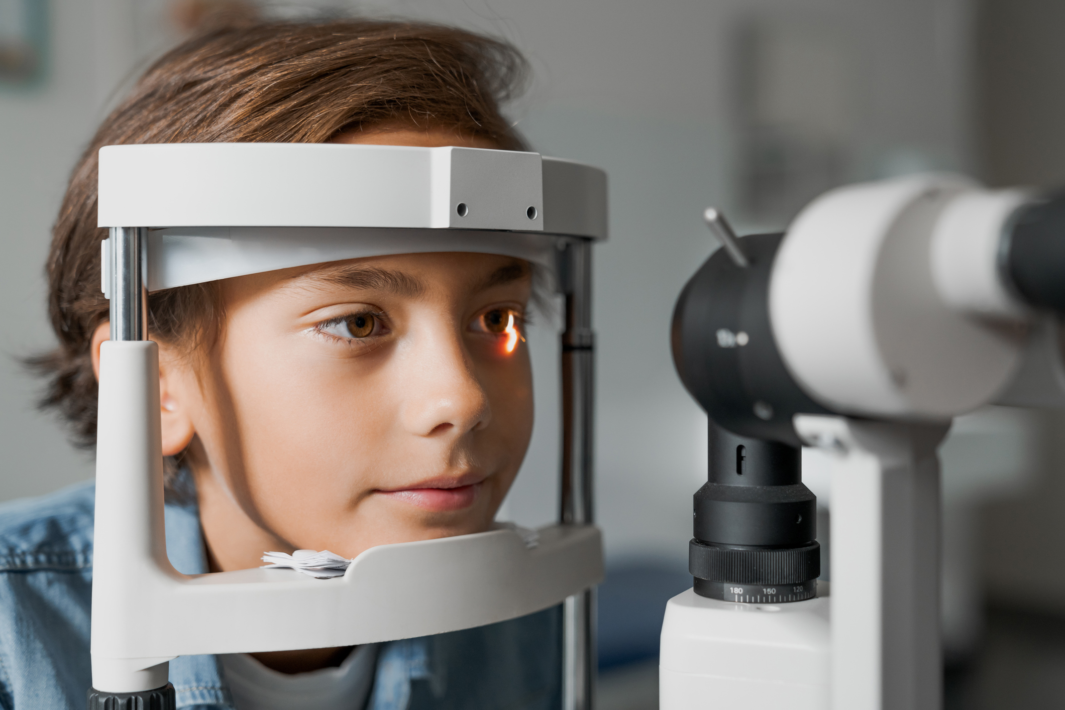 Close up shot of boy checking vision with tonometer at eye clinic