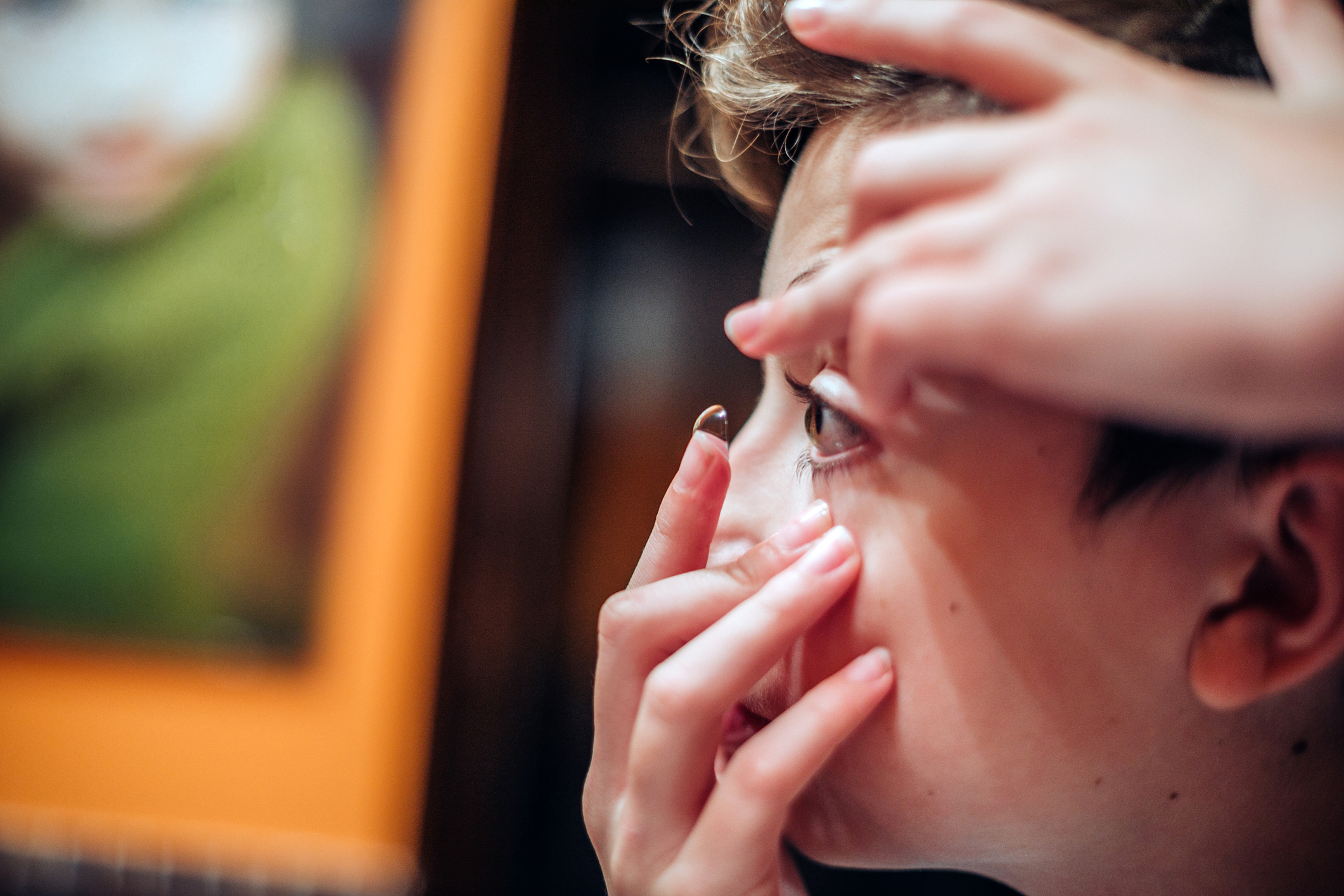 teenager boy putting his contact lenses in front of mirror