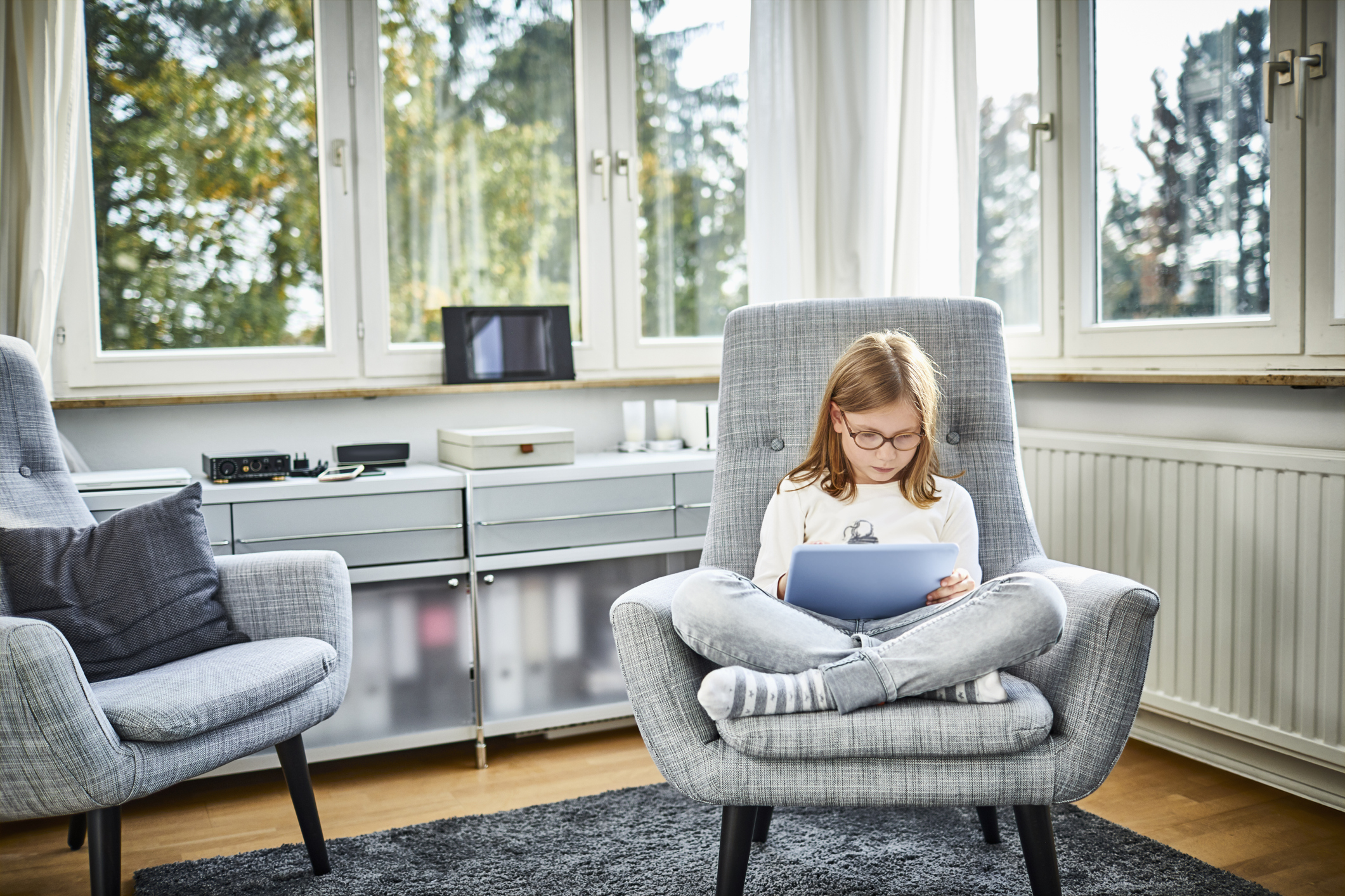 Girl sitting in armchair using digital tablet at home