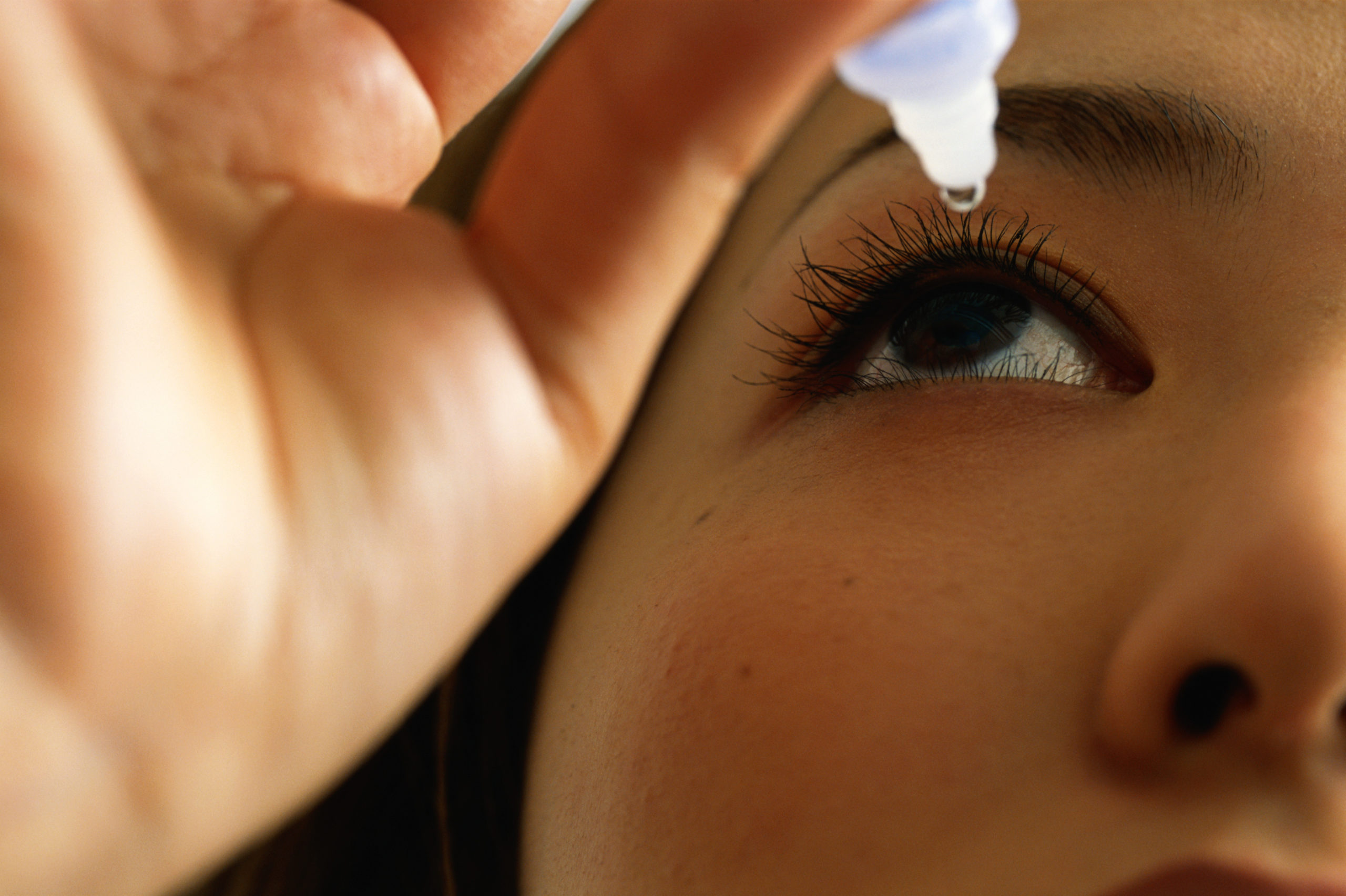 Woman using eye drops, close-up