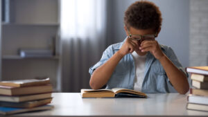 A photo of a child rubbing his eyes, indicating dry eye