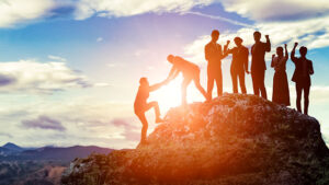 A group helping someone up a mountain