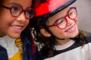Two young girls wearing glasses and smiling