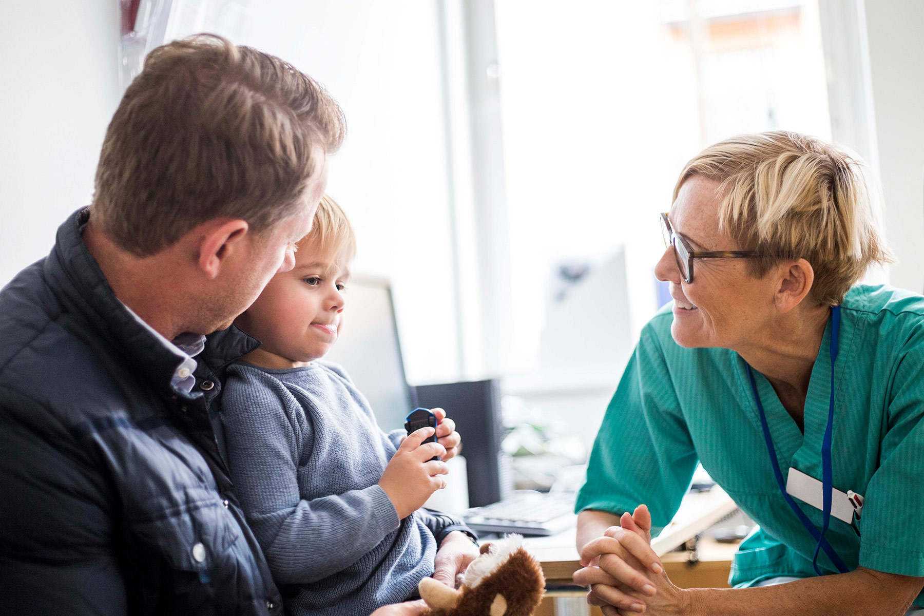 A friendly pediatrician talking with father and son, together navigating myopia care