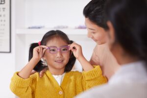 A young girl tries on a pair of glasses