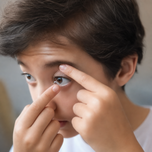 A young boy inserts a contact lens