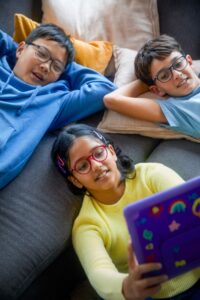 A group of kids wearing SightGlass Vision's DOT spectacles while looking at an iPad 